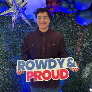 Photo of Kevin Munoz holding "Rowdy & Proud" sign.