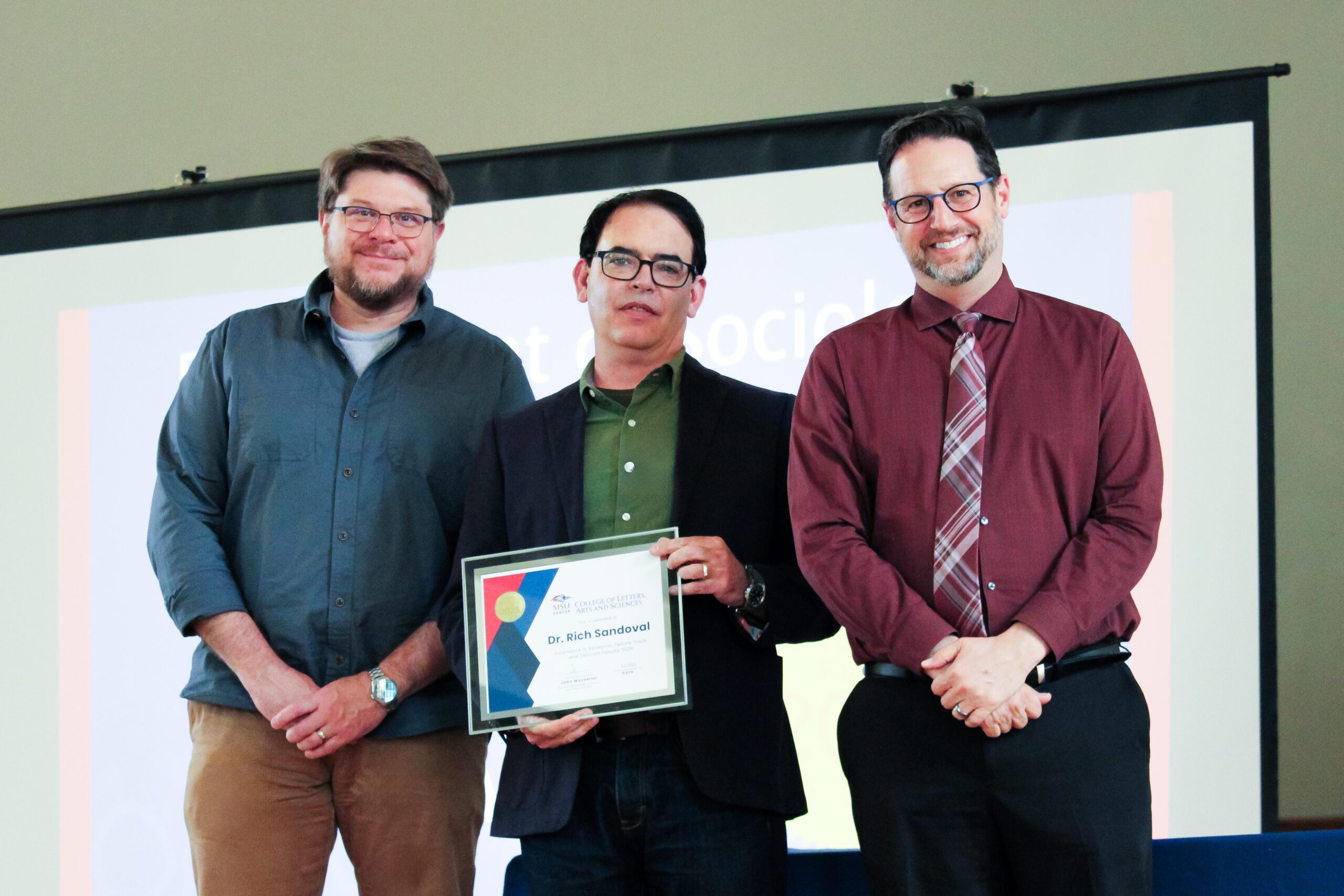 Dr. Rich Sandoval receiving the 2025 CLAS Excellence in Research Award. Pictured from left to right: Dr. Todd Yokley, Associate Chair of Sociology and Anthropology; Dr. Rich Sandoval, Award Recipient; and Dr. John Masserini, CLAS Dean.