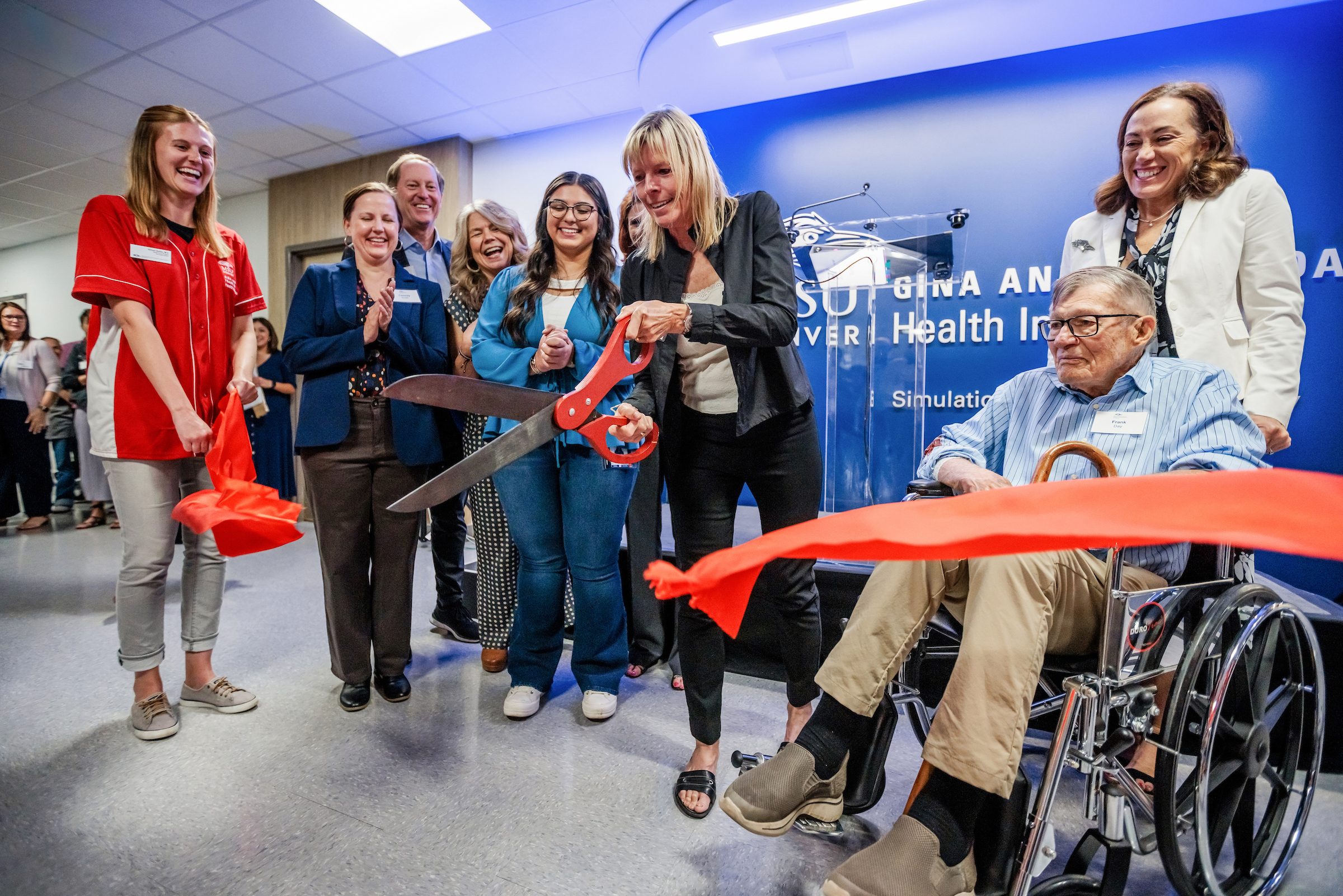 The Day Health Institute team surrounds Gina and Frank Day as they cut a red ribbon in front of the Interprofessional Simulation and Skills Laboratory