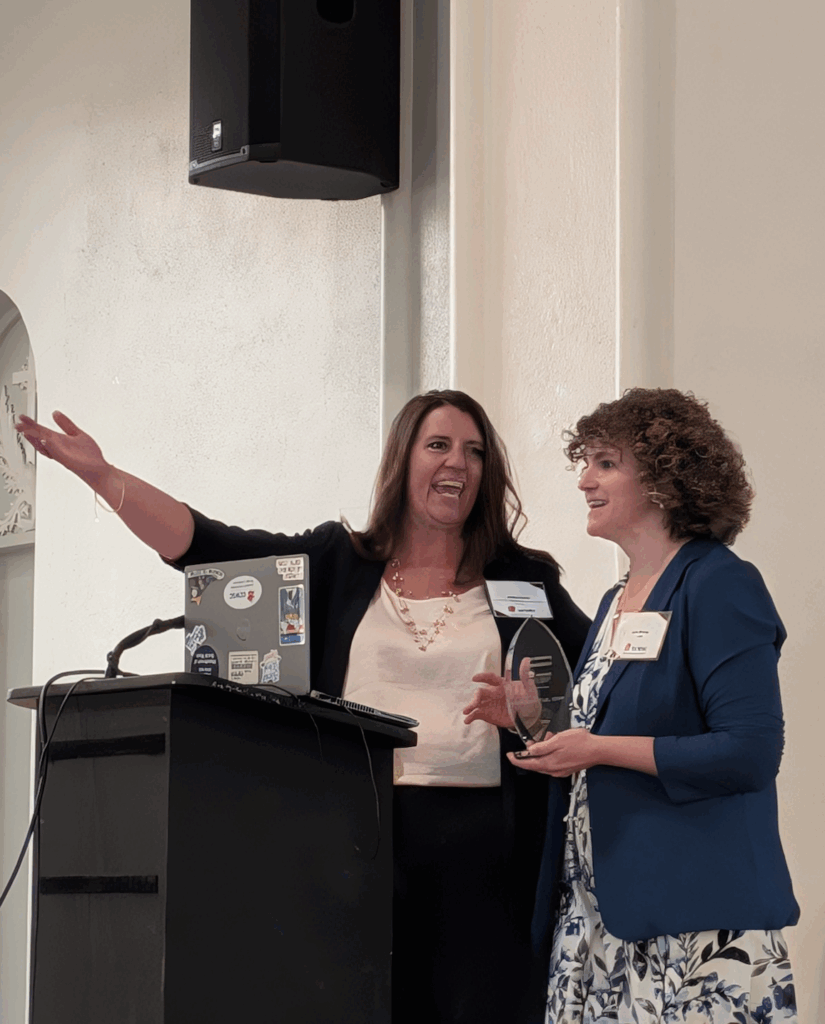 Kathy Clark (left), Colorado Department of Human Services, Division of Child Welfare, Learning & Development Team; and Lara Bruce on stage at St. Cajetan's