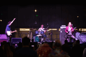 three people in a band singing and playing instruments on stage