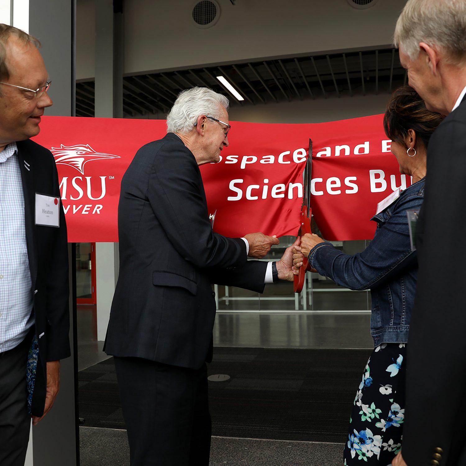 a large pair of scissors cuts the red ribbon at the AES Ribbon Ceremony