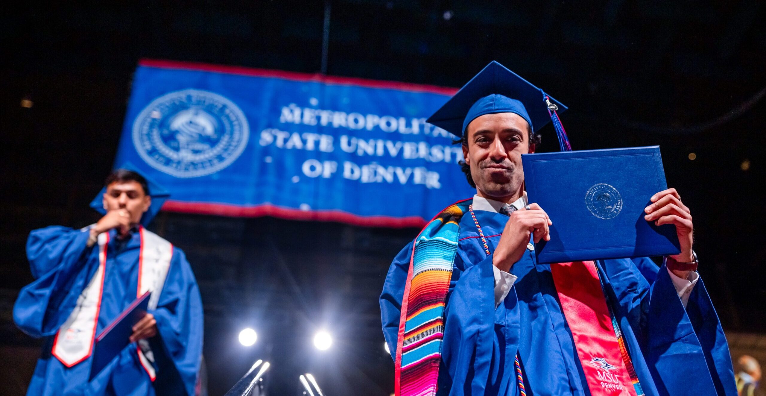 Grad having fun and showing off diploma while walking off stage.
