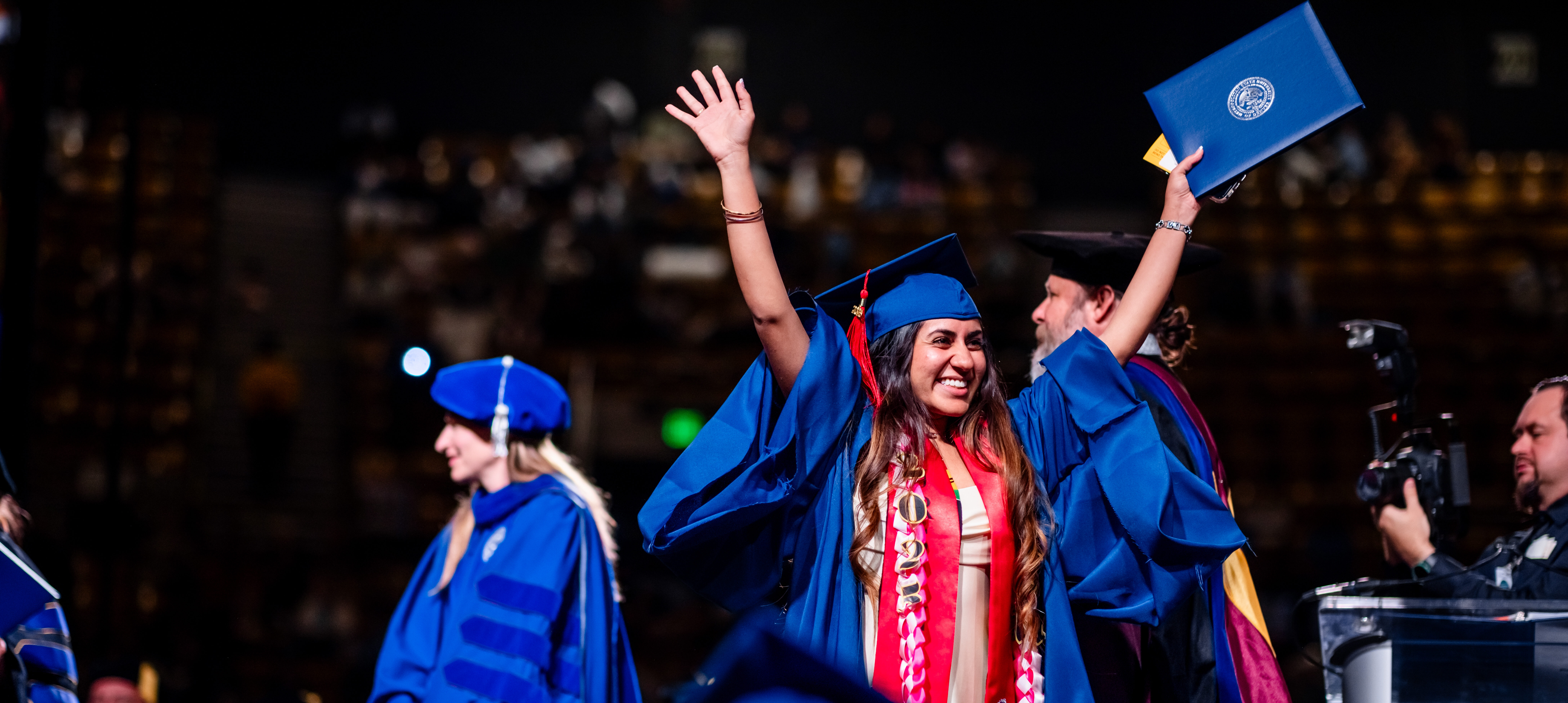 Grad celebrating getting their diploma by waving arms up high.