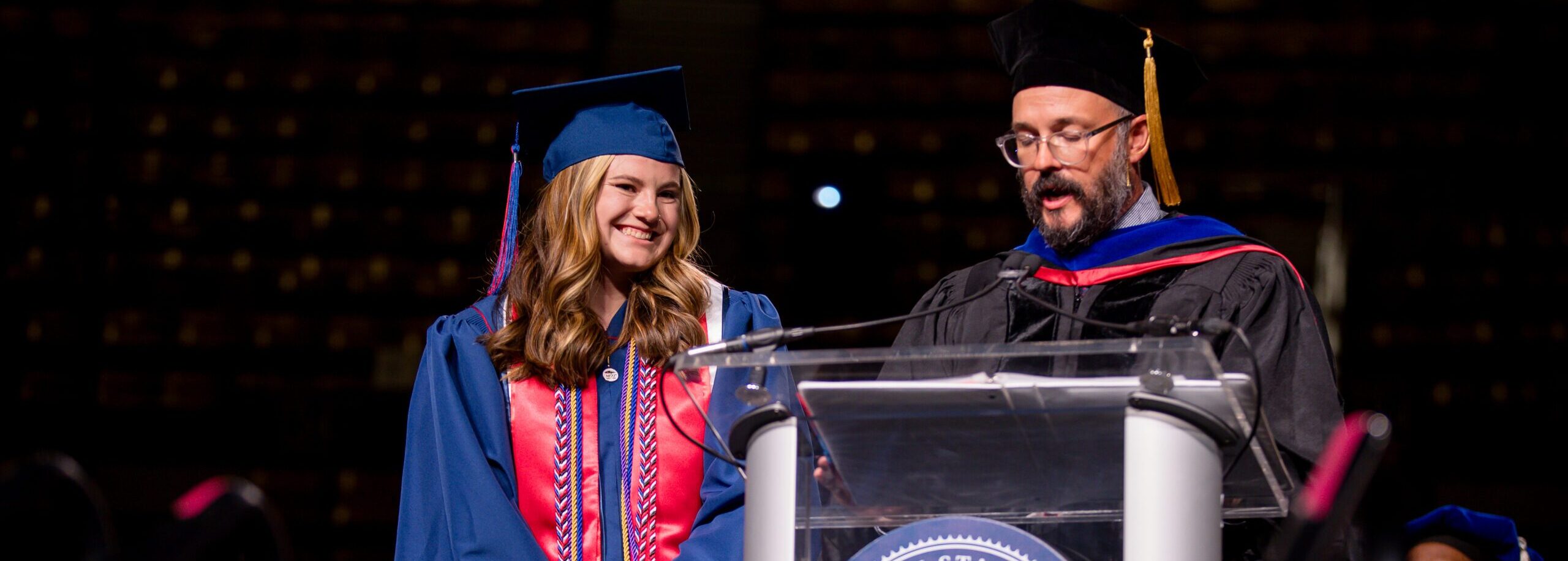 Hailey Glass stands next to Senior Associate Dean, Dan Lair while he introduces her during the Commencement Ceremony.