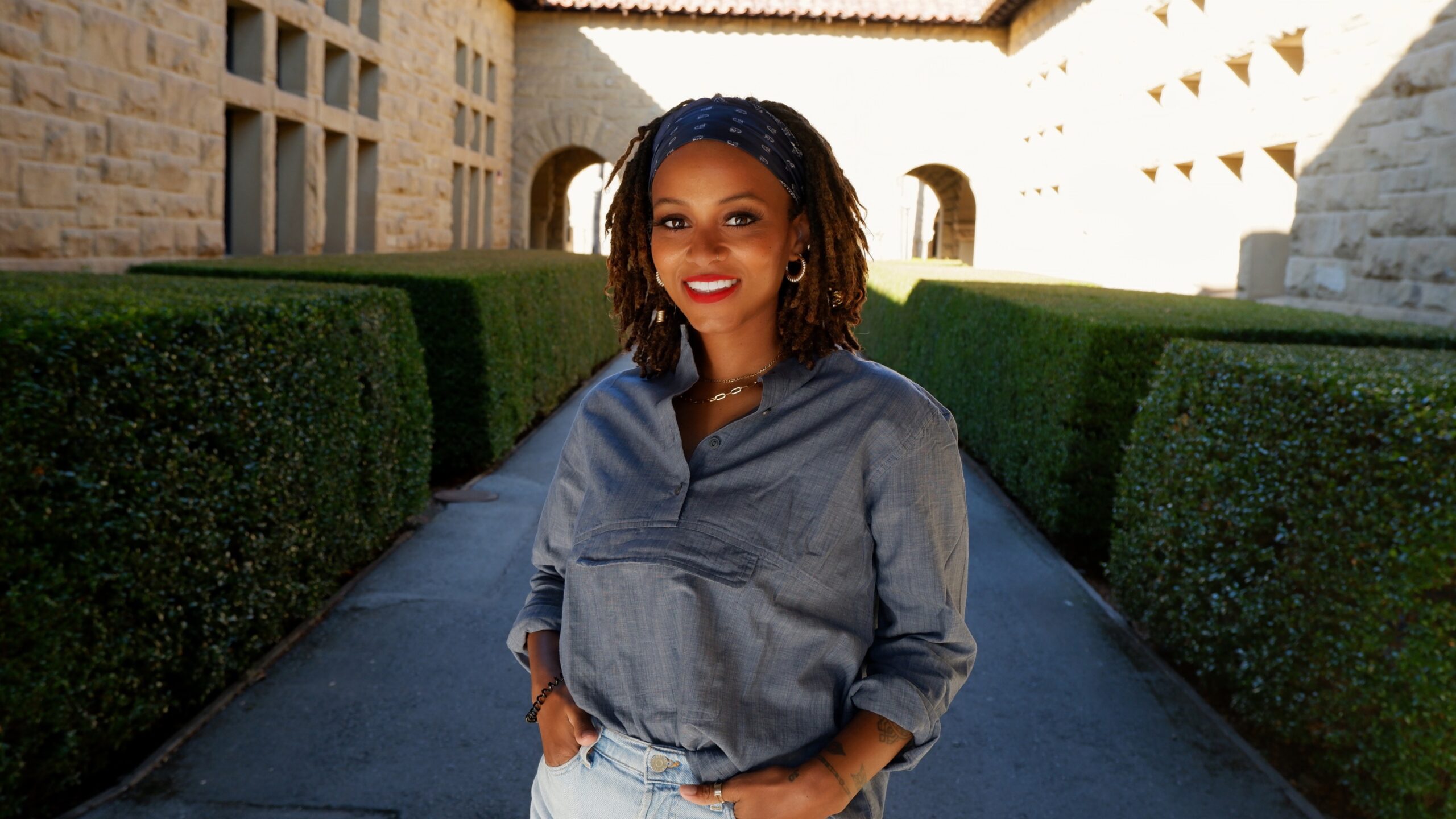 Profile image of Shanice Webb, standing and smiling with hands on hips.