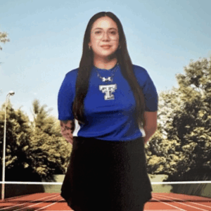 A young woman with long brown hair wearing a blue shirt and black skirt