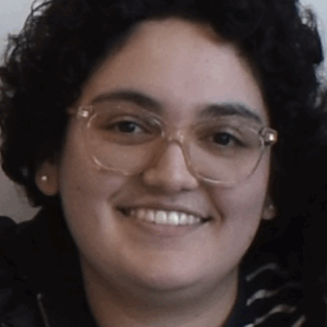 A young woman with short curly hair and glasses