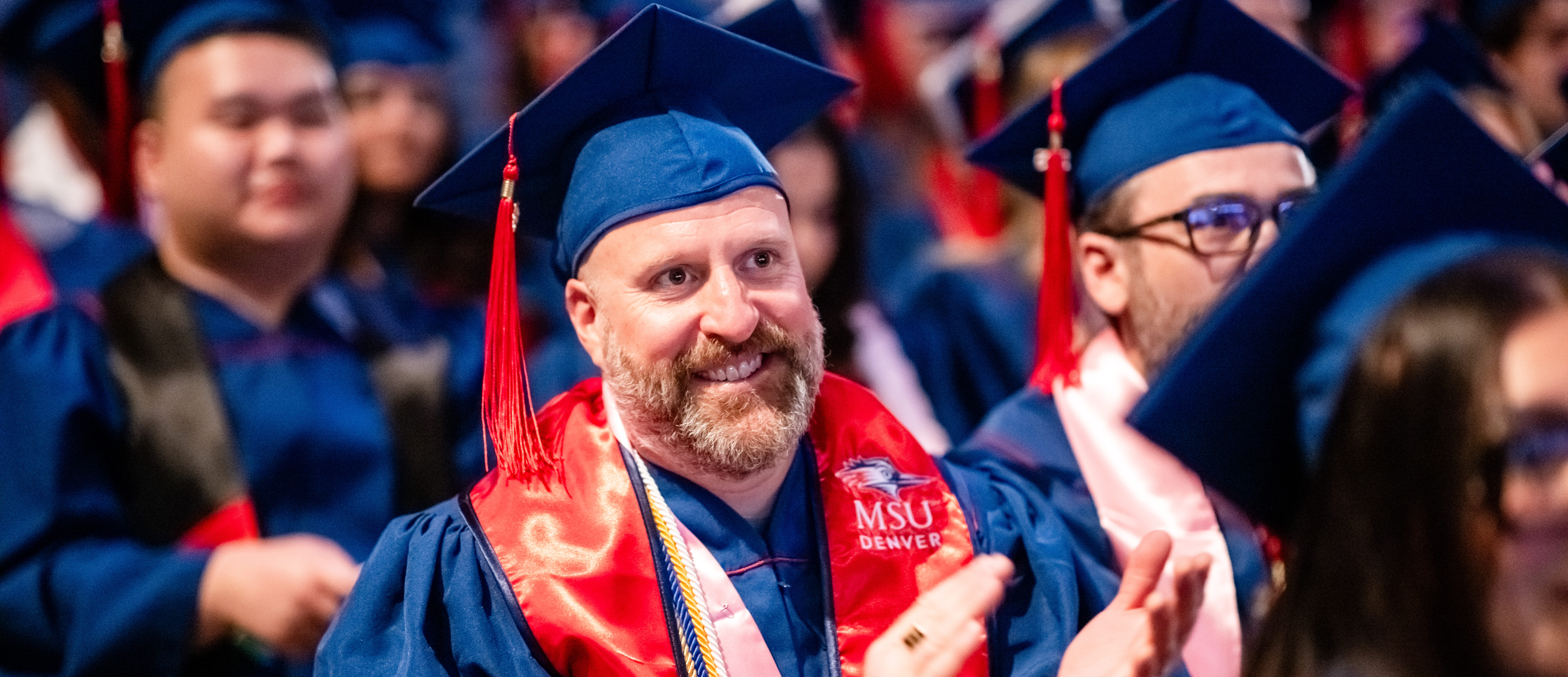 Grad smiling and clapping during the ceremony.