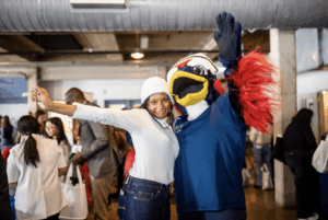 A student and Nurse Rowdy posing with arms outstretched in the Tivoli Turnhalle