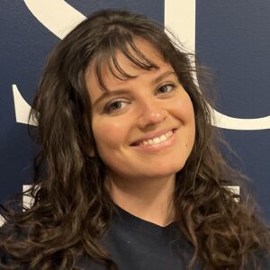 A young woman with curly brown hair and bangs