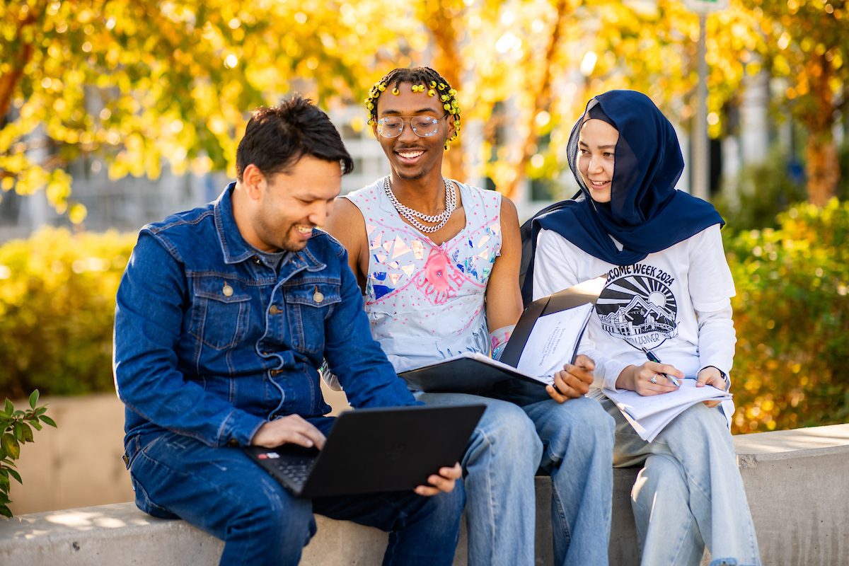 3 MSU Denver Students looking at a notebook and a tablet