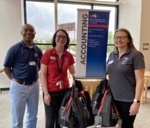 Fall 2025 MPAcc Orientation _Leadership team (Greg, Lauren, and Letitia) standing in front of accounting department table top sign in lobby
