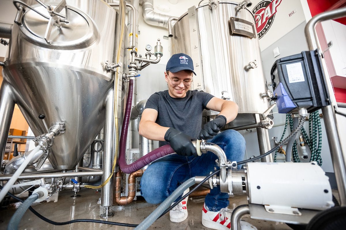 Student cleaning the fermentor in the Brewing Science and Technology class.