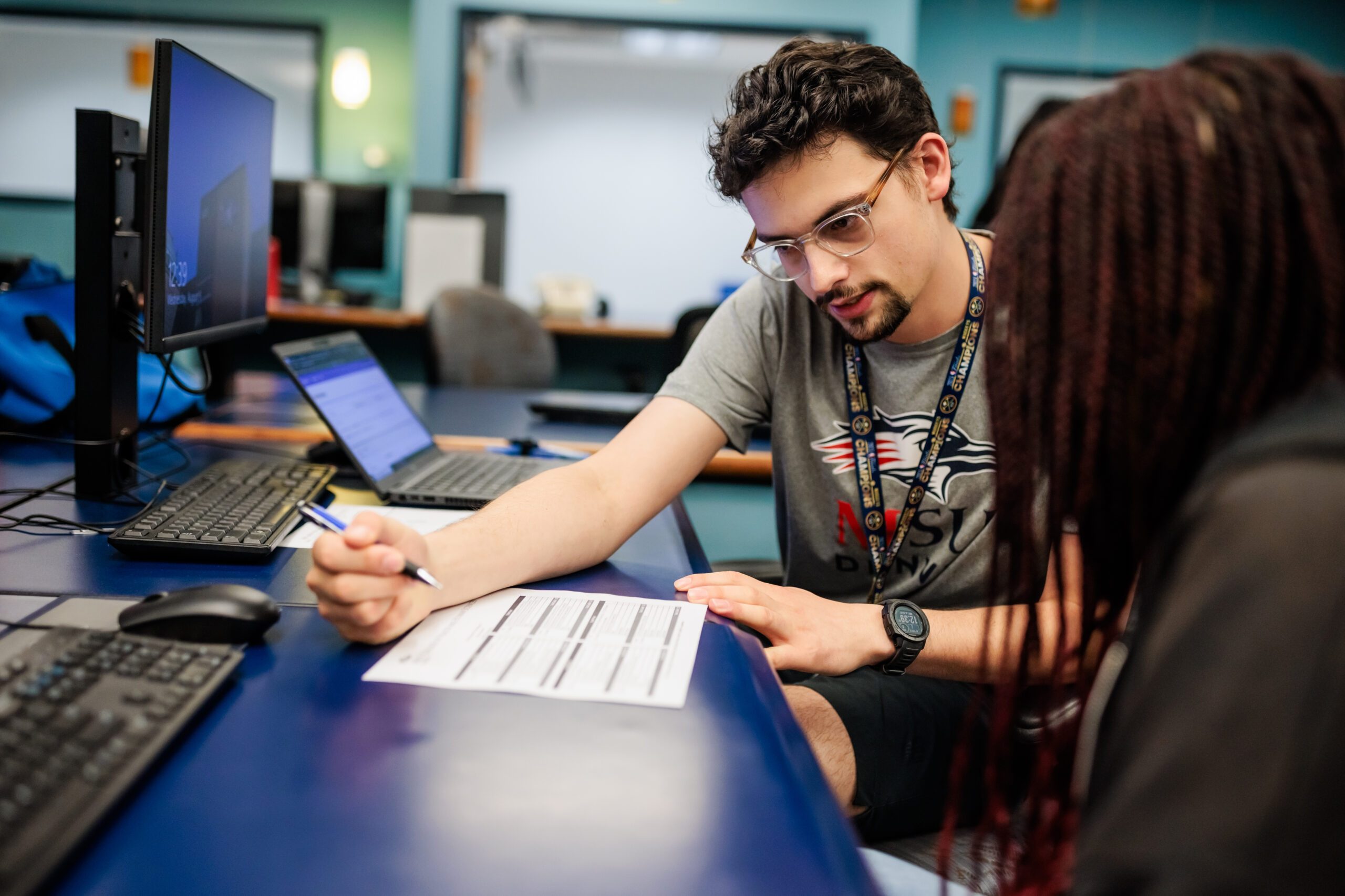 Photo of an advisor and a student looking over an advising guide in a computer lab.