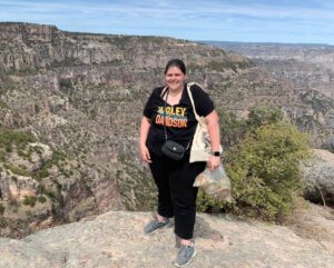 Dr. Bingham-Byrne standing on a rocky overlook with a canyon landscape in the background