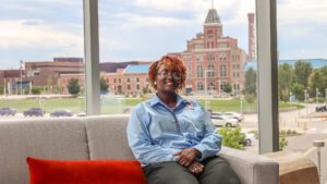 MSU Denver student Sanaa Walker sitting on a couch in the Hotel and Hospitality Learning Center with the Tivoli in the background