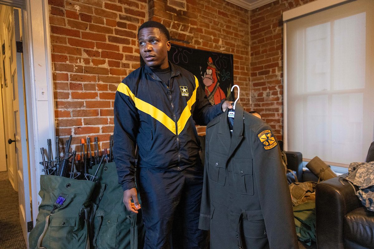 Student holds his commissioning ceremony jacket.
