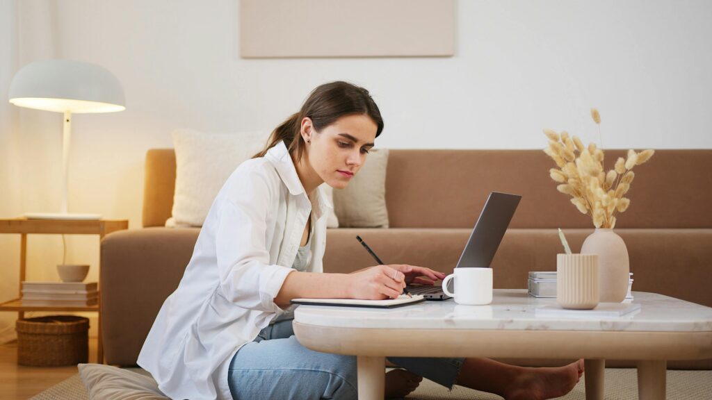 A person in a white shirt writing with a pencil and paper on a table.