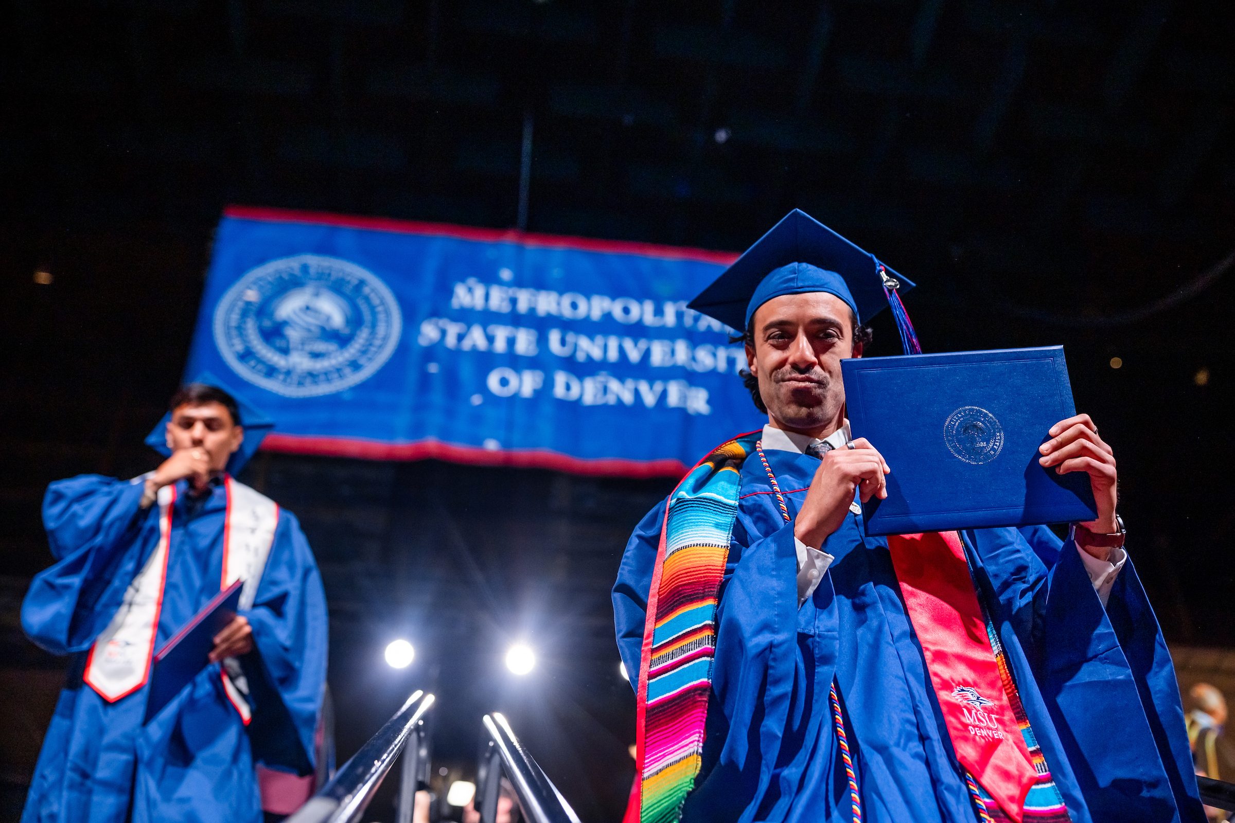 Student holding up diploma while walking down steps