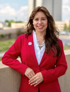 Woman with long brown hair dressed in a red suit. 