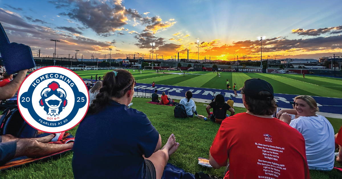 Students look over a soccer field at sunset.