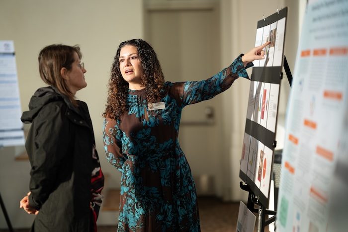 Two people discussing a presentation board at a conference or symposium.