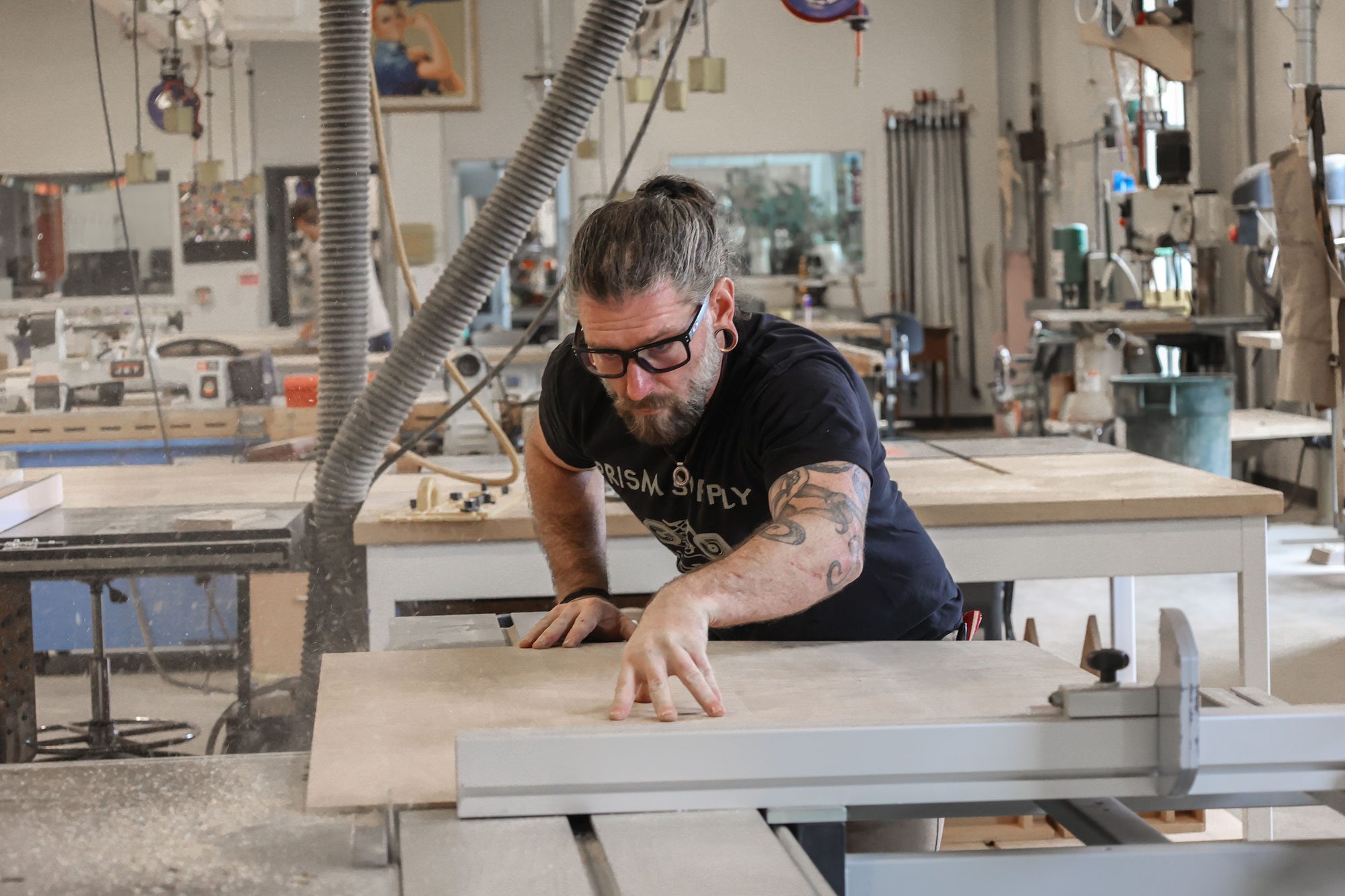 MSU Denver student Adam Wolf cutting a piece of wood on newly-donated equipment from the Hartman family