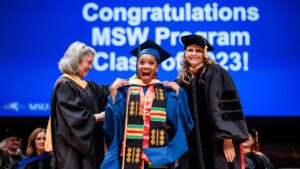 A student looking really excited and happy after receiving their MSW hood