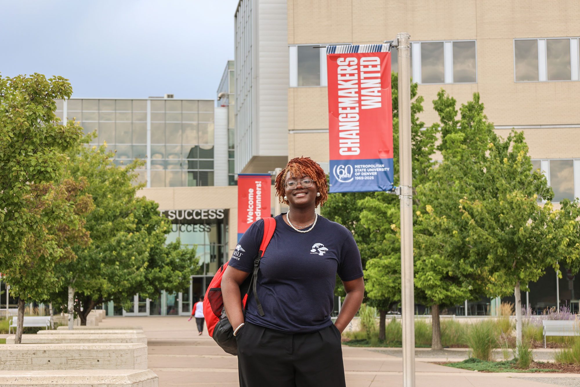 MSU Denver student Sanaa Walker standing in front of JSSB and a Changemakers Wanted sign