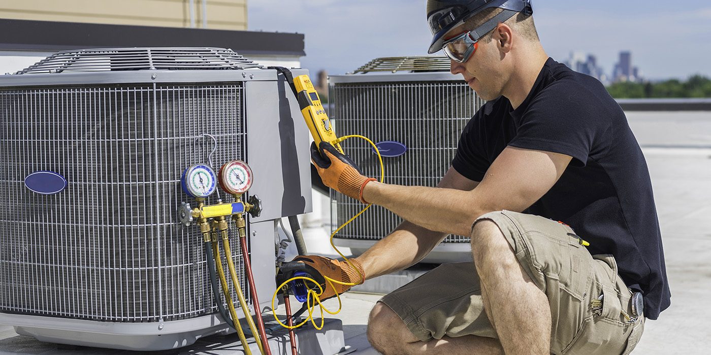 Man on roof working on HVAC for building