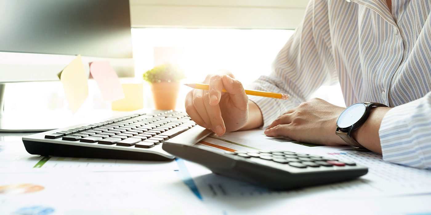 Close up of hands working with a computer keyboard and a calculator