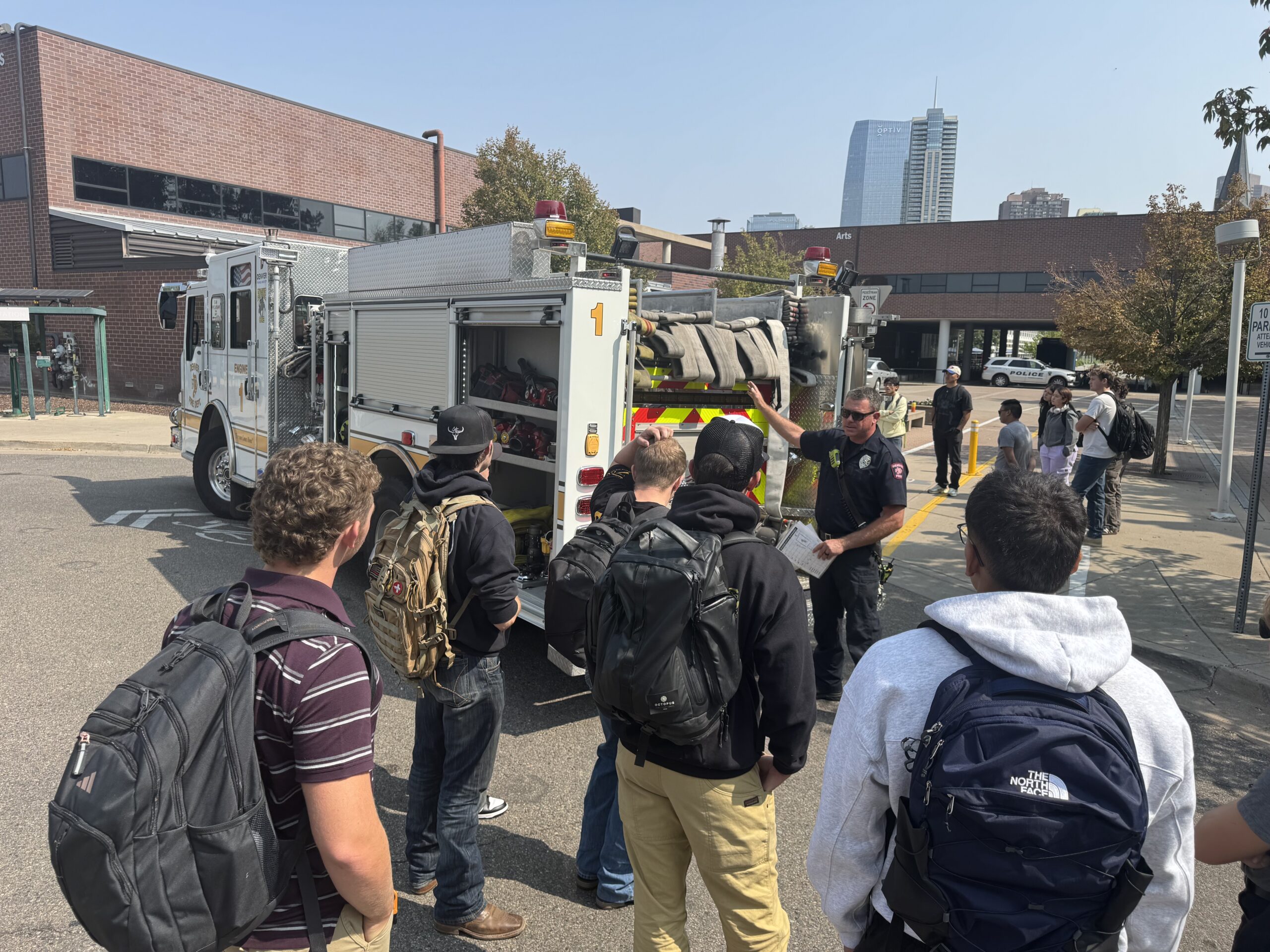 Kids stand near fire truck listening to instructions from fire chief.