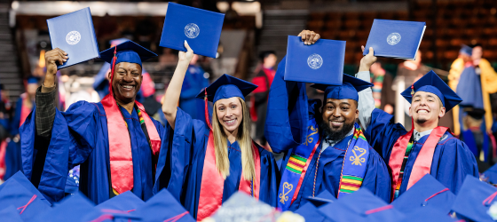 Afternoon Ceremony Graduates holding their diplomas with smiling faces