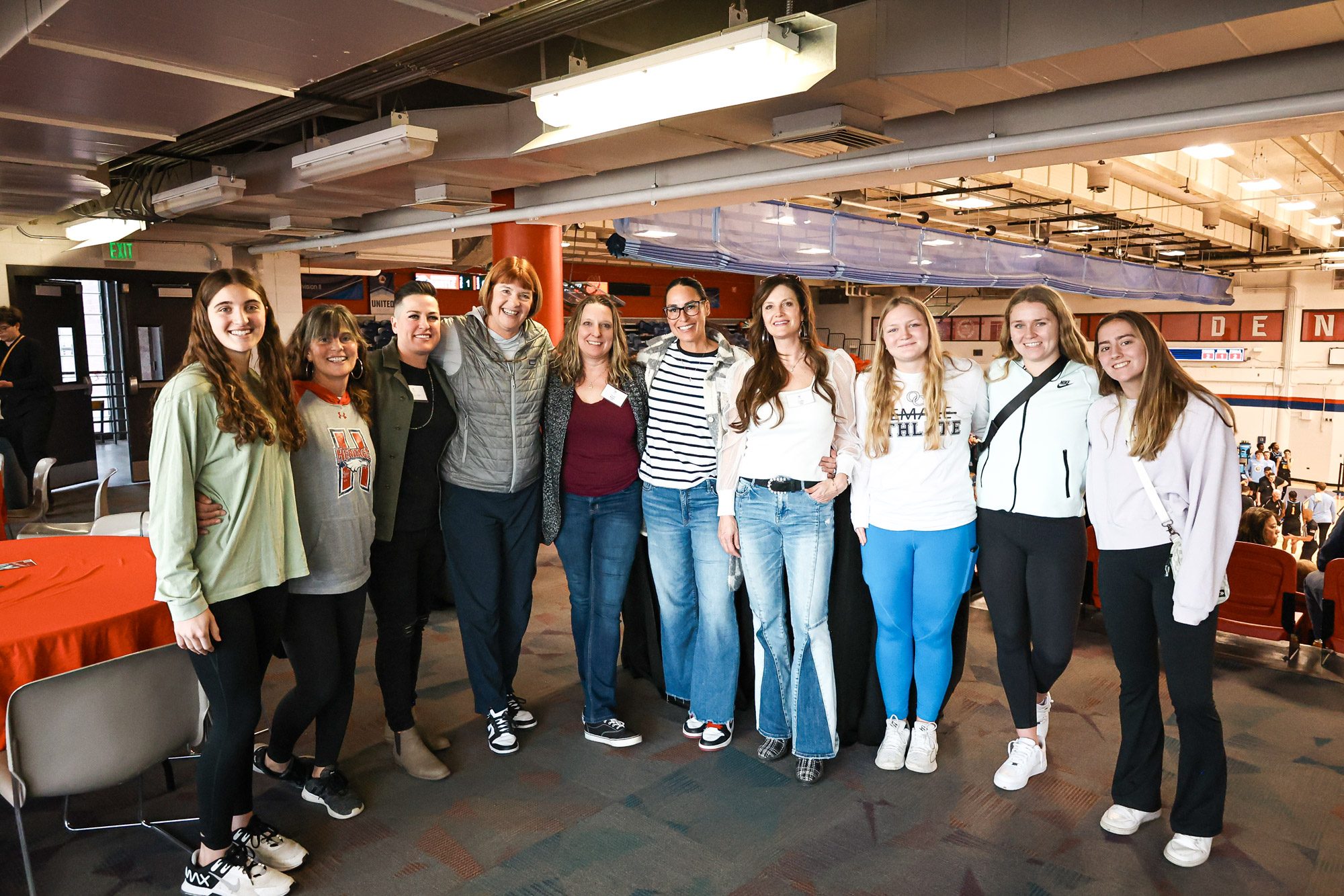 A large group of women and girls posing for a photo at an MSU Denver basketball game