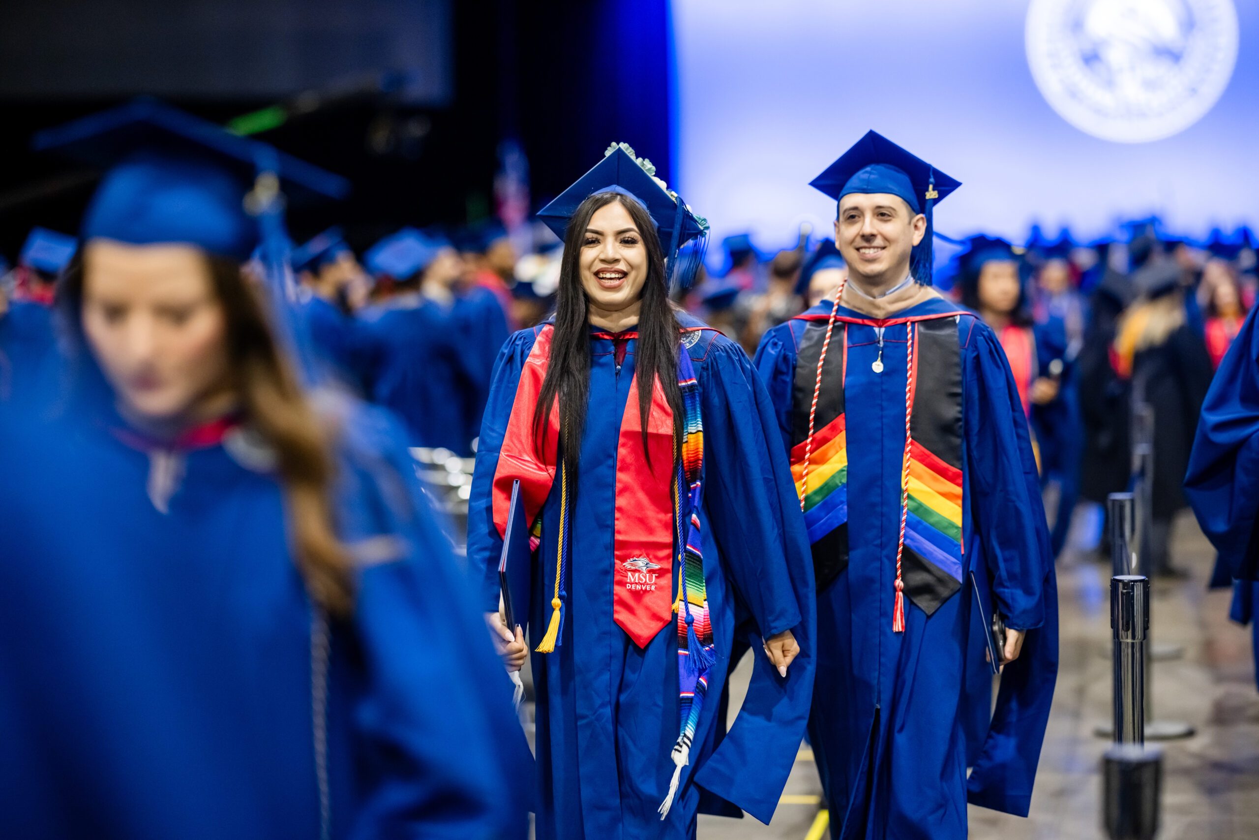 Fall '25 Commencement Ceremony - 2 MPAcc grads, Alondra and Zach, walking out in line of event space