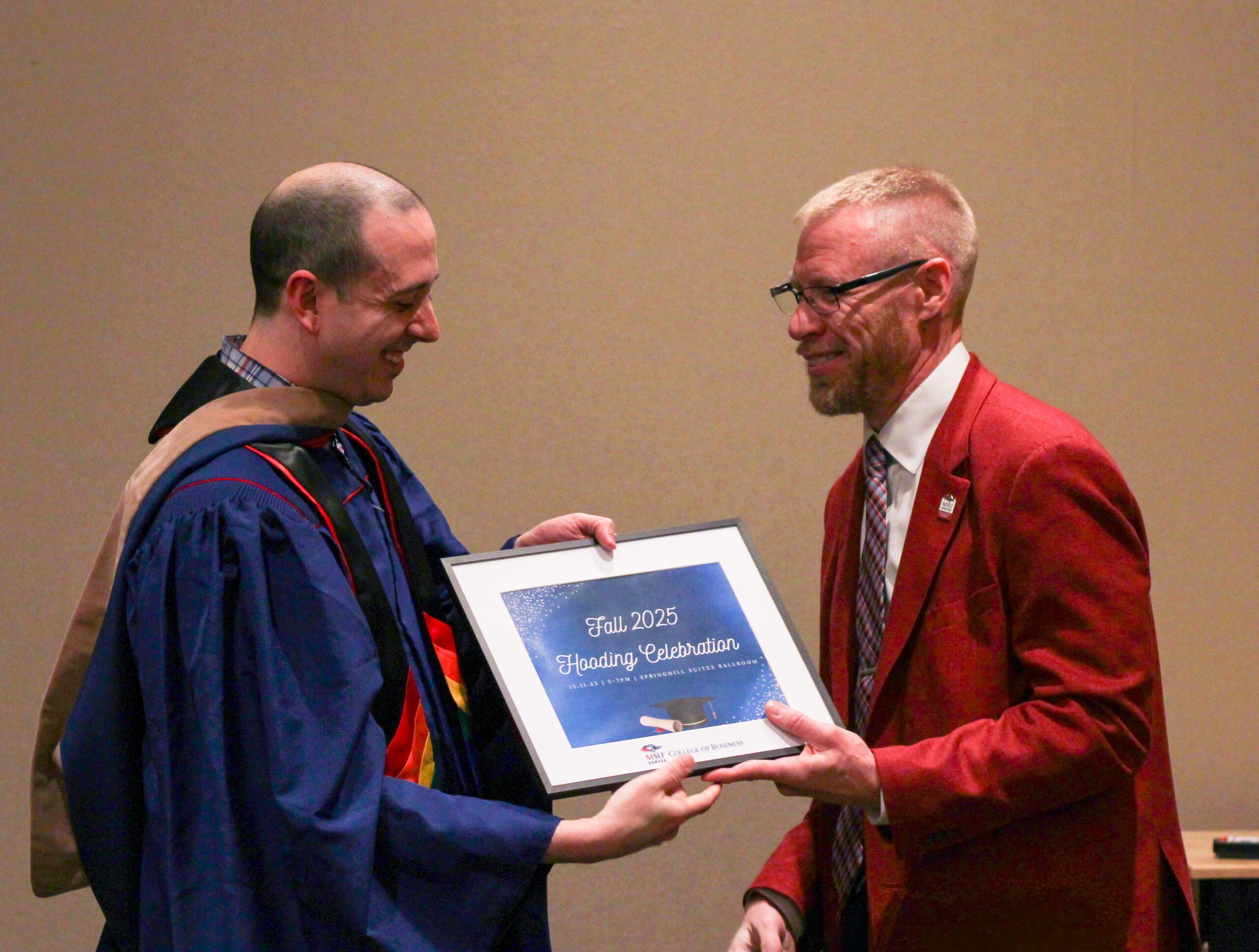Fall '25 MBA & MPAcc Hooding Celebration - Interim Dean giving MPAcc grad, Zach, a diploma frame