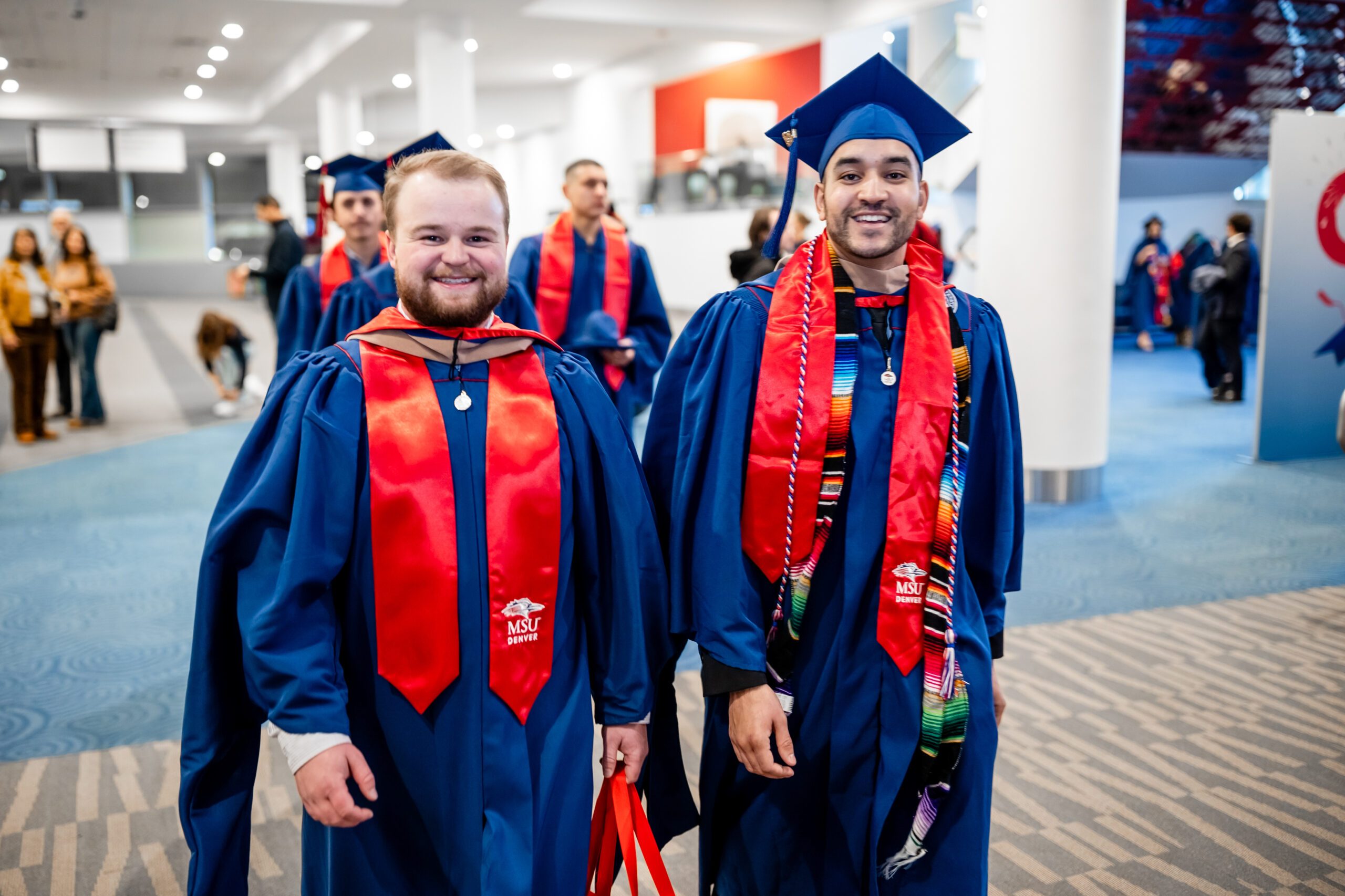 Fall '25 Commencement Ceremony - 2 MPAcc grads, Joe and Kevin, walking outside of event space in regalia