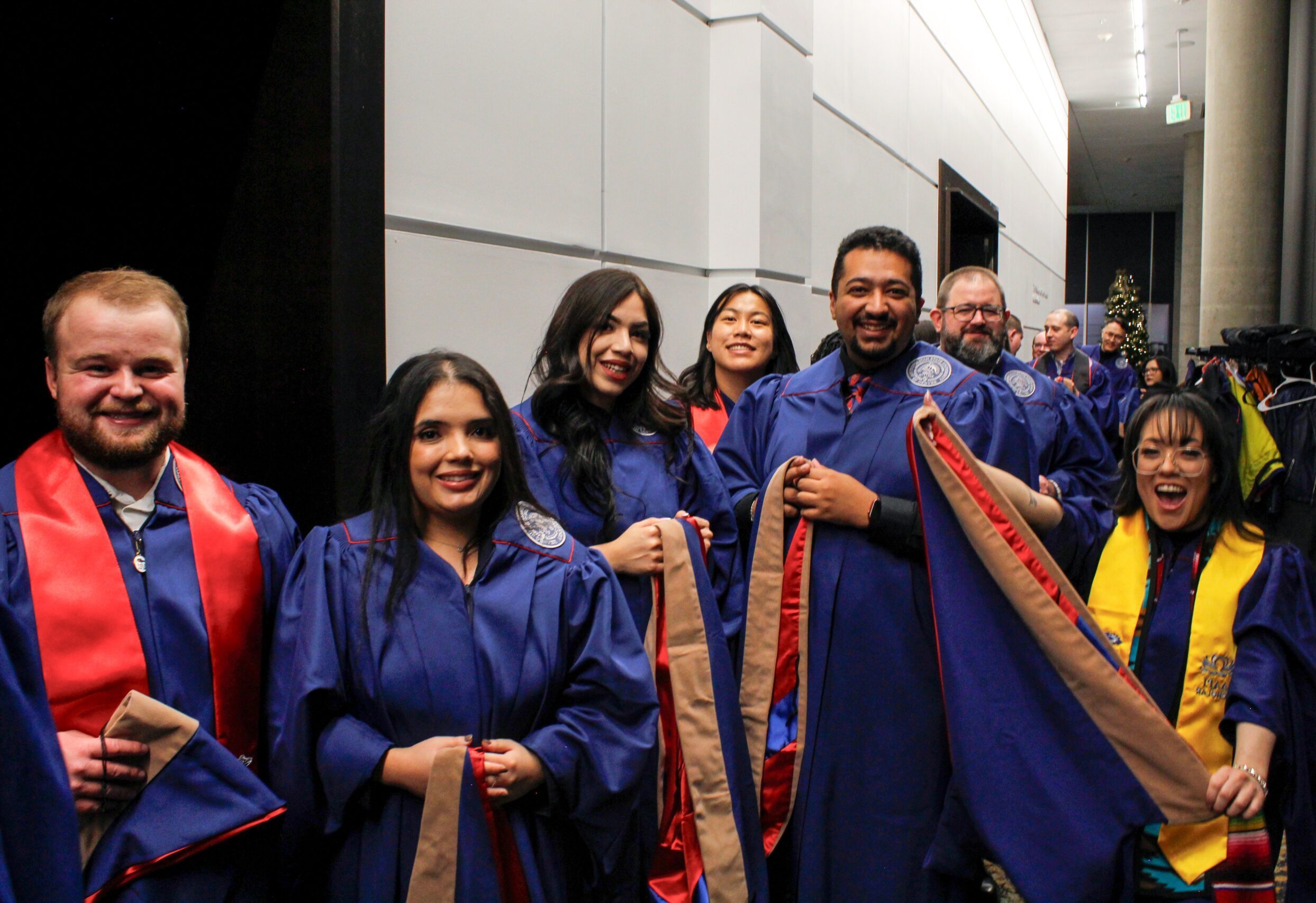 Fall '25 MBa & MPAcc Hooding Celebration - 7 MPAcc grads lining up outside banquet hall holding hoods