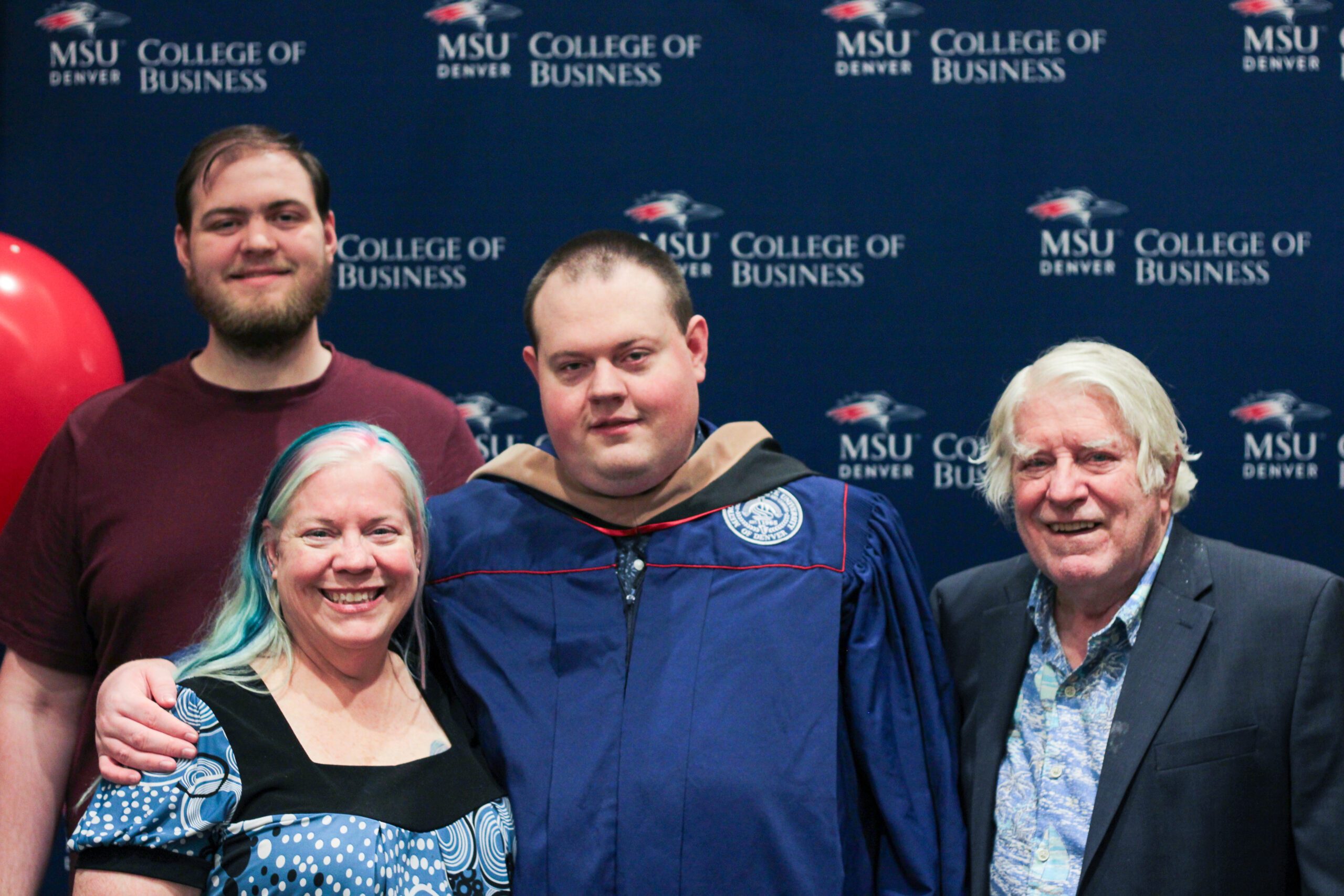 Fall '25 MBA & MPAcc Hooding Celebration - MPAcc grad, Matt, in regalia smiling with 3 family members