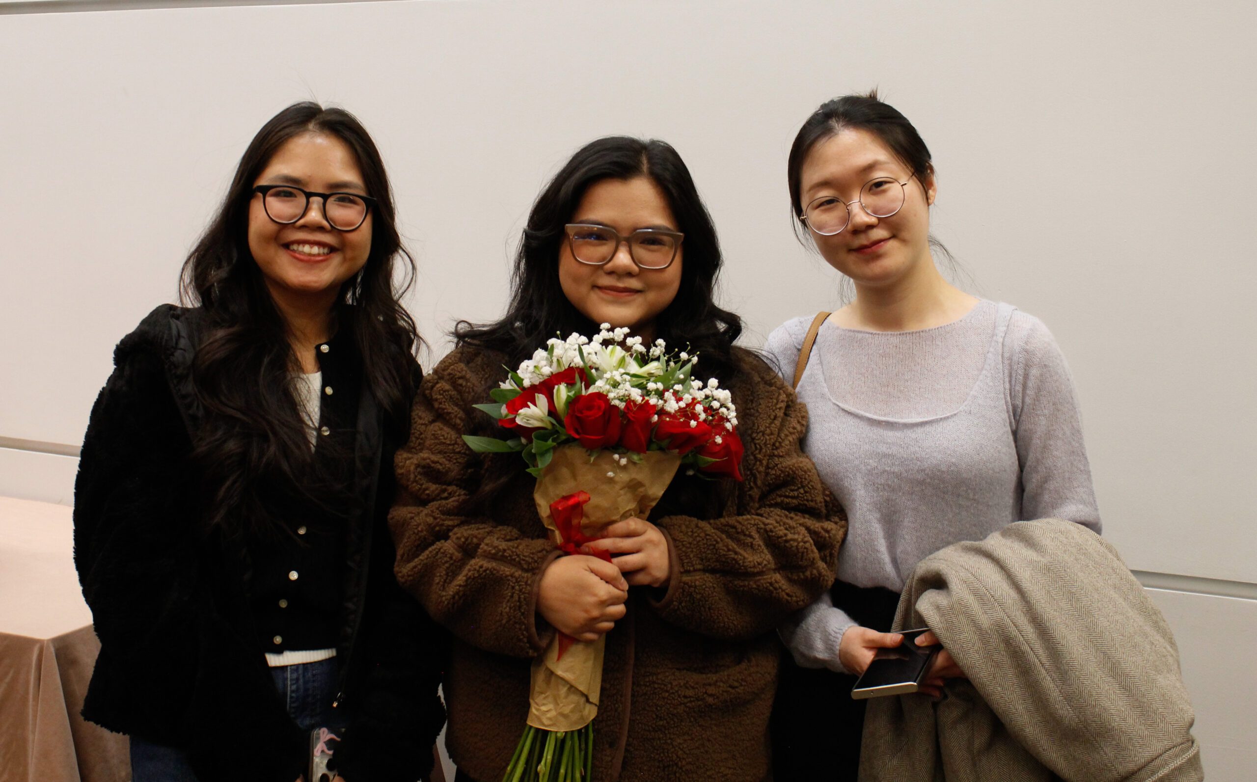 Fall '25 MBa & MPAcc Hooding Celebration - MPAcc Grad, Tram, holding flower bouquet with family