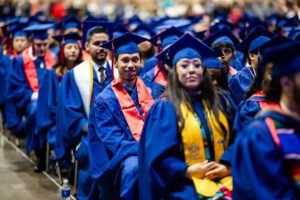 Fall '25 Commencement Ceremony - accounting grads front and center smiling as they are seated and listening to the speaker