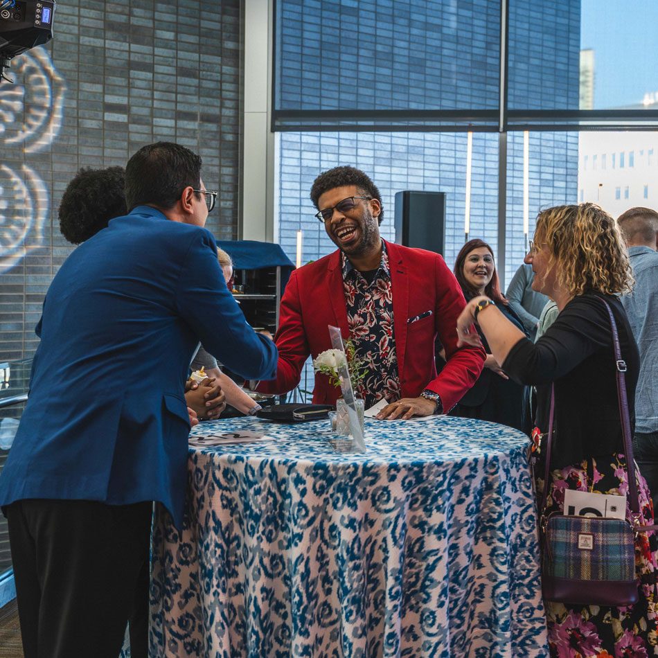 three event goers chatting over a table at a networking event
