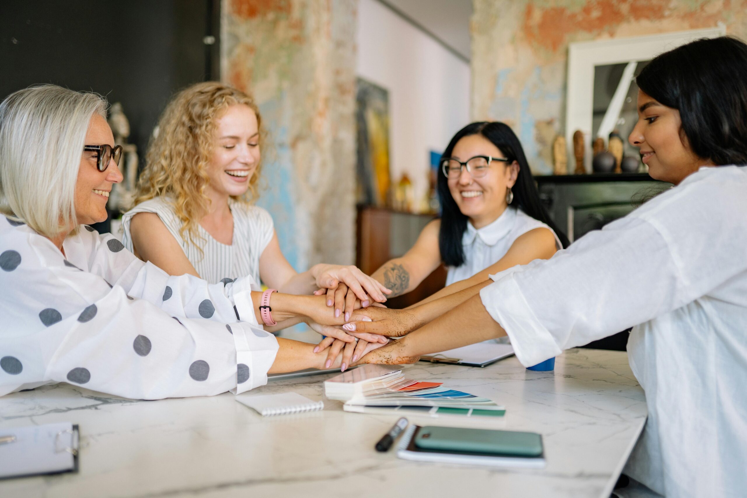 Women sitting at a table shaking hands.