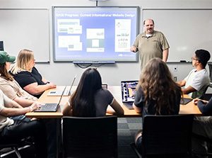 Daniel Pittman, Ph.D., assistant professor of Computer Science at Metropolitan State University of Denver, works with students in his classroom.