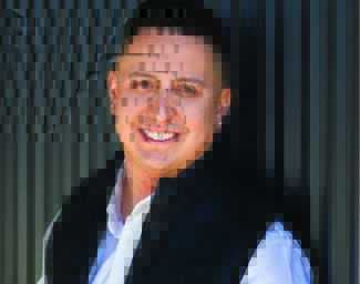 Man with short dark hair, black vest with a white shirt underneath.