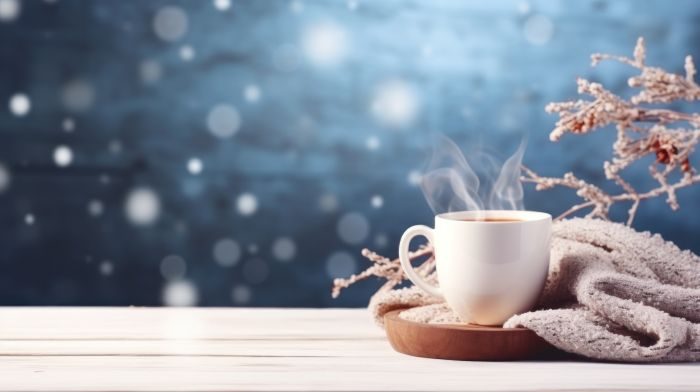 A warm drink in a mug steams against a snowy background