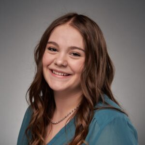 A woman with long, brown hair wearing a blue blouse