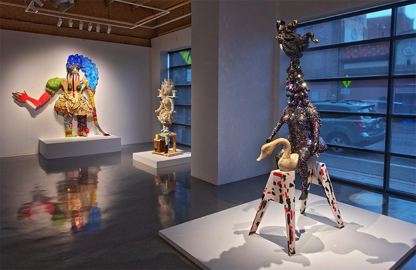 An art gallery displaying colorful and abstract sculptures on pedestals.