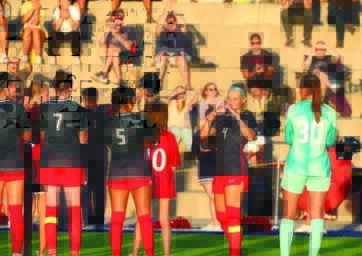 Soccer players line up with the backs to us. One player turns and smiles at the camera.